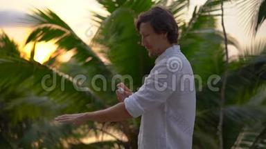 一个年轻人用防蚊剂喷在皮肤上的超慢镜头。 热带背景